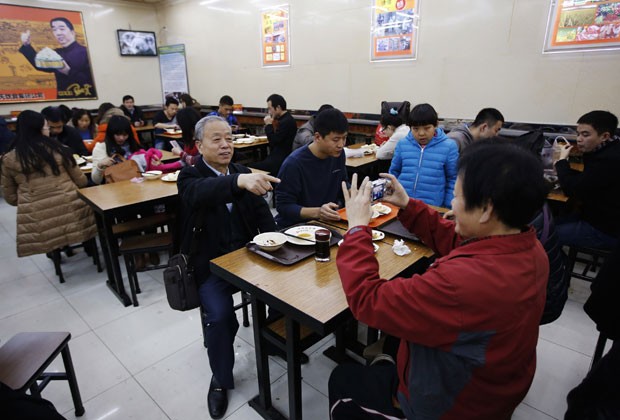 Família tira foto em mesa usada pelo presidente chinês para comer pouco antes em restaurante de Pequim (Foto: Kim Kyung-Hoon/Reuters)