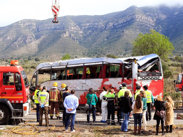 Equipes de resgate trabalham no local onde um ônibus colidiu com um carro na Espanha (Foto: Pau Barrena/AFP)