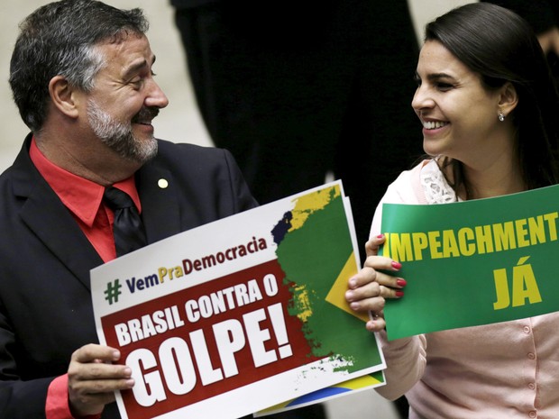 16/04 - Os deputados Paulo Pimenta (PT-RS) e Mariana Fonseca (PSDB-RO) exibem cartazes contra e a favor do impeachment durante sessão no plenário da Câmara dos Deputados, em Brasília, na manhã deste sábado (16) (Foto: Ueslei Marcelino/Reuters)