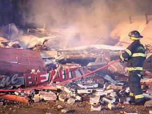Bombeiro inspeciona danos causados por incêndio em um pequeno shopping em Ferguson na madrugada desta terça-feira (25) (Foto: Scott Olson/Getty Images/AFP)