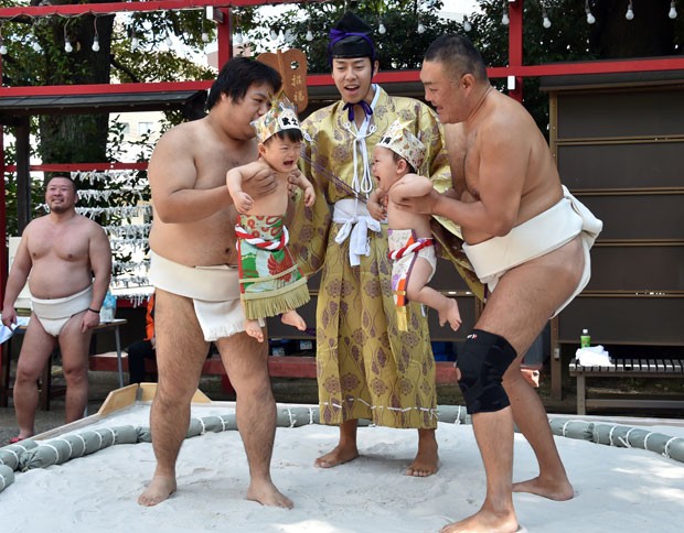 Crianças são seguradas por lutadores de sumô, com objetivo de fazê-las chorar. (Foto: Yoshikazu Tsuno/AFP)