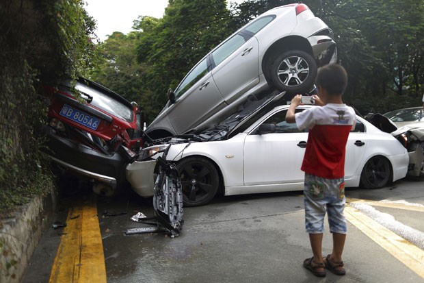 Menino tira foto de carros empilhados após acidente na China nesta segunda-feira (4) (Foto: Reuters)