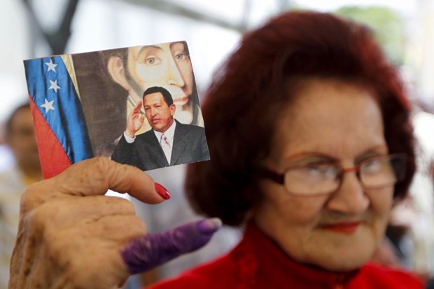Partidária mostra foto de Chávez durante oração nesta quinta-feira (20) em Caracas (Foto: Reuters)