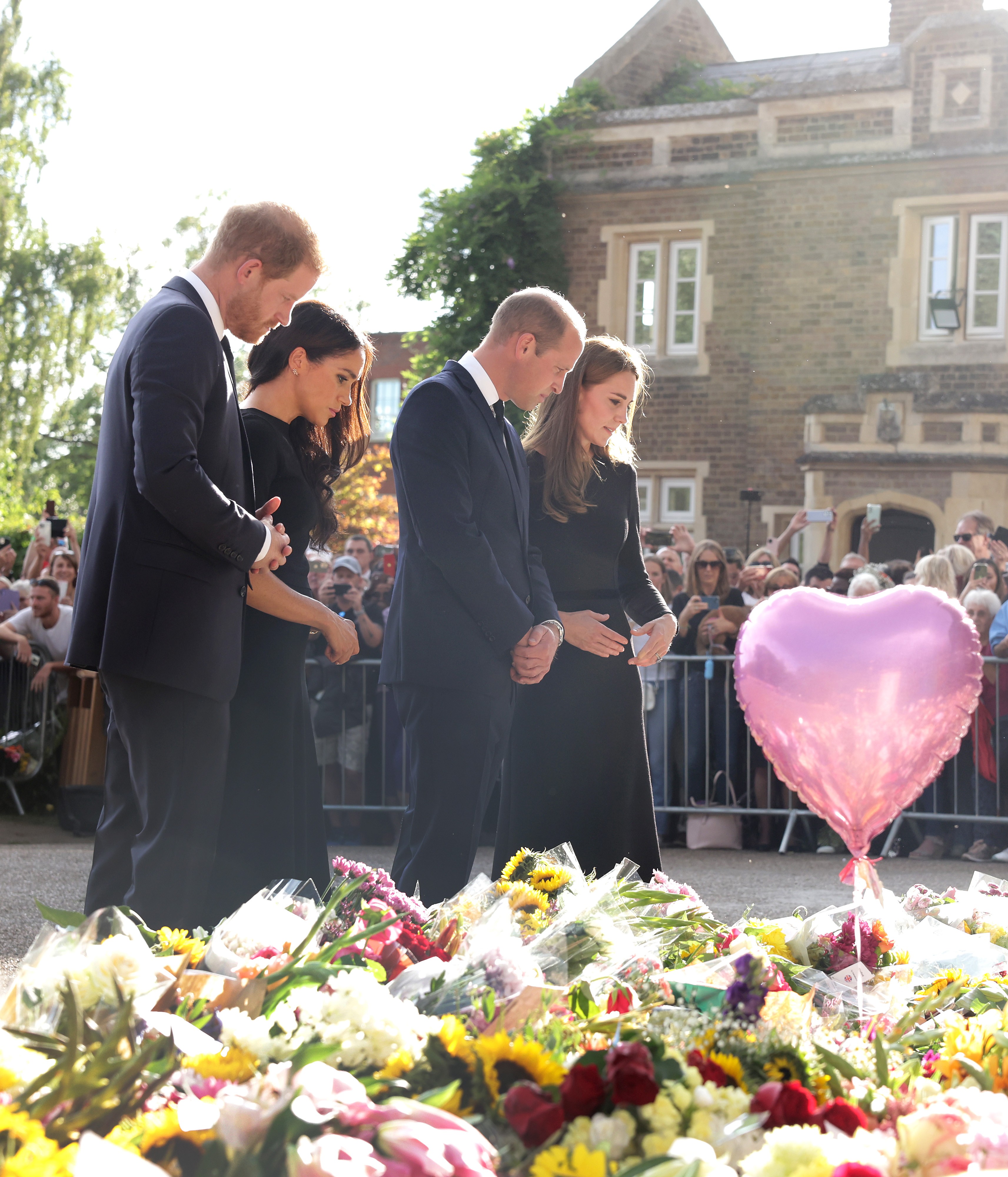 A Duquesa Kate Middleton, o Príncipe William, o Príncipe Harry e a atriz e Duquea Meghan Markle nos portões do Palácio de Windsor vendo as flores e as cartas deixadas pelos súditos reais em homenagem à Rainha Elizabeth II (1926-2022) (Foto: Getty Images)