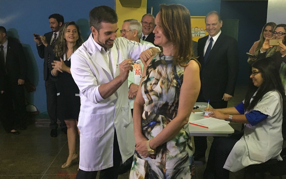 Diretora da Escola Classe da 302 Norte, em Brasília, Tânia Pierre recebe vacina contra a gripe do secretário de Saúde (Foto: Luiza Garonce/G1)