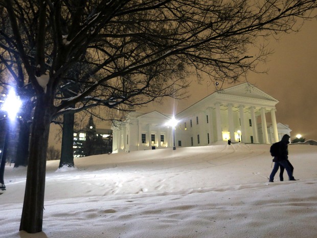 Casal caminha em área coberta pela neve no Estado da Virgínia na noite desta sexta-feira (22) (Foto: Steve Helber/AP Photo)