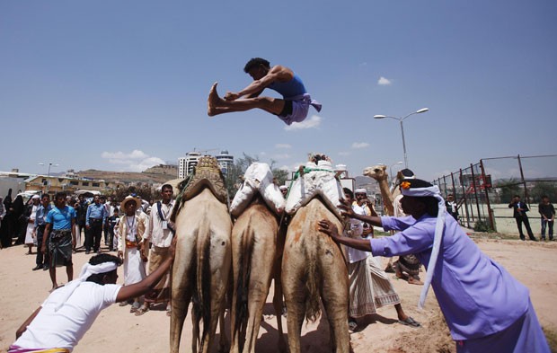 Participante de festival de verão, em Sanaa, no Iêmen, salta sobre três camelos  (Foto: Khaled Abdullah/Reuters)