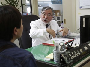 O cirurgião Kim Seok-Kwun com um paciente em seu consultório (Foto: Ahn Young-joon/AP)