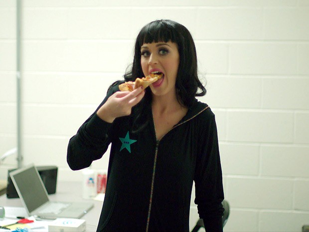 Às pressas, a cantora Katy Perry traça um pedaço de pizza nos bastidores de um dos shows da turnê retratada no documentário 'Part of me' (Foto: Divulgação)