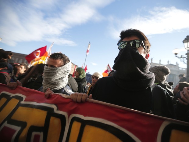 Manifestantes cobrem o rosto durante protesto neste sábado (14), em Turim, na Itália, contra políticas de austeridade (Foto: MARCO BERTORELLO / AFP)