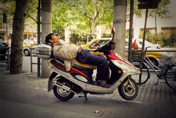 Homem dorme em uma moto na China (Foto: Divulgação/Eric Leleu)