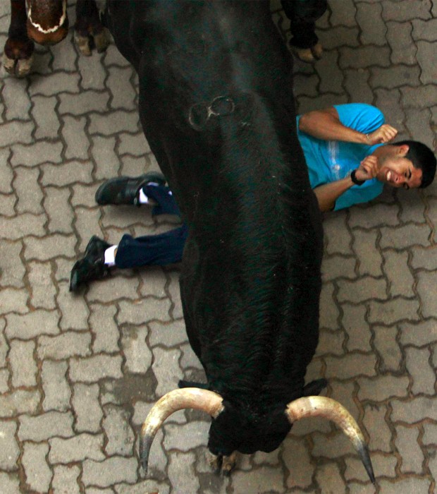 Corredor é derrubado por touro no terceiro dia da corrida do festival de São Firmino em Pamplona (Foto: Reuters)
