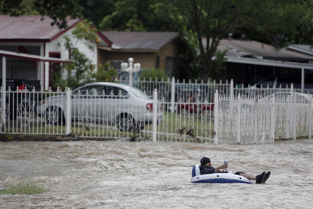 Morador enfrenta enchente com boia e cerveja na Califórnia (Foto: AP/San Antonio Express-News, Lisa Krantz)
