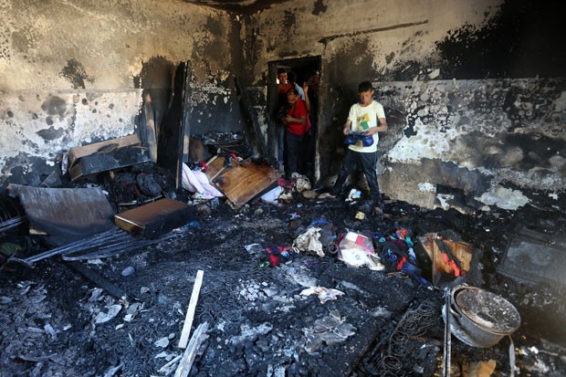 Palestinos olham estragos causados após incêndio em casa na Cisjordânia nesta quinta-feira (30); um bebê morreu (Foto: Jaafar Ashtiyeh/AFP)