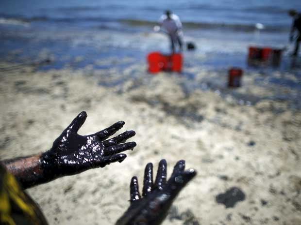 Homem mostra mãos sujas de óleo durante limpeza de praia na califórnia. (Foto: Lucy Nicholson / Reuters) Homem mostra mãos sujas de óleo durante limpeza de praia na califórnia. (Foto: Lucy Nicholson / Reuters)