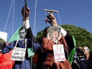 Manifestantes seguram fantoches representando o primeiro-ministro de Portugal, Pedro Passos Coelho, e a chanceler da Alemanha, Angela Merkel, nesta segunda-feira (12) em Lisboa (Foto: AFP)