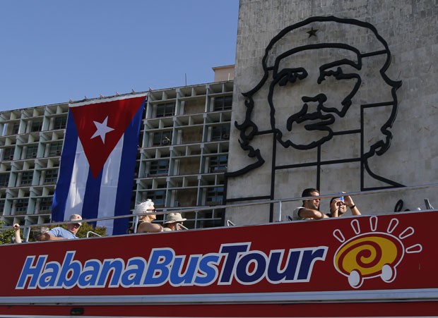 Turistas em ônibus de dois andares passam por escultura de ferro do guerrilheiro Ernesto Che Guevara em Havana (Foto: Desmond Boyland/AP)