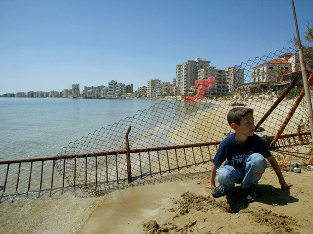  Em foto de 2003, garoto grego-cipriota posa em frente à cerca que separa área abandonada de Varosha (Foto: AP Photo/Petros Karadjias)