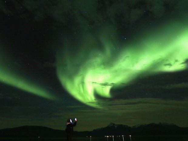 Turista fotografa a aurora boreal em Mestervik, na Noruega (Foto: Yannis Behrakis/Reuters)