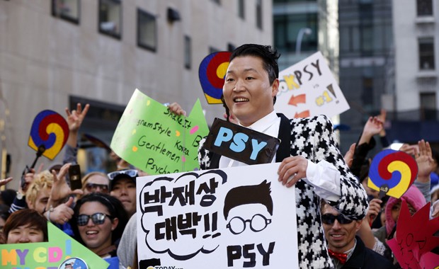 Psy posa com cartazes de fãs na rua em Nova York durante gravação do programa 'Today' (Foto: Reuters/Lucas Jackson)