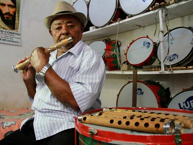 Mestre Bia toca pífano na sala onde guarda instrumentos e ensaia com a banda (Foto: Waldson Costa / G1)