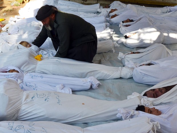 Homem cuida do corpo de uma criança morta entre outras vítimas de ataque na região de Ghouta, no bairro de Duma, em Damasco, na Síria. Ativistas dizem que elas foram mortas em ataque químico. (Foto: Bassam Khabieh/Reuters)