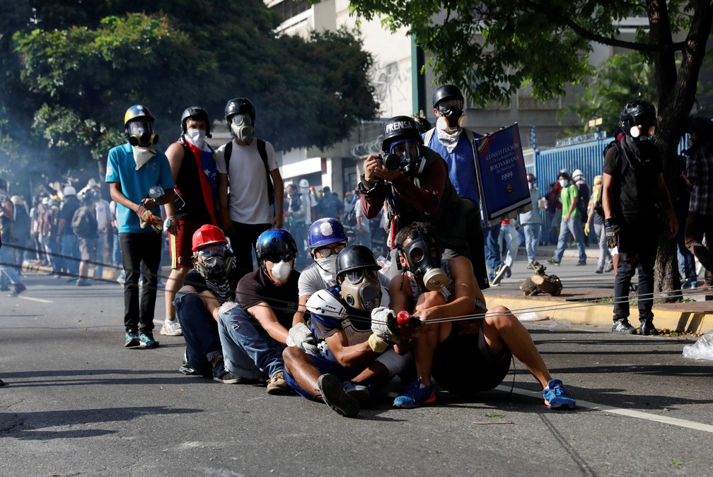 Opositores usam estilingue para jogar bomba de fezes contra forças de segurança nesta quinta-feira (18) em Caracas (Foto: REUTERS/Carlos Garcia Rawlins )