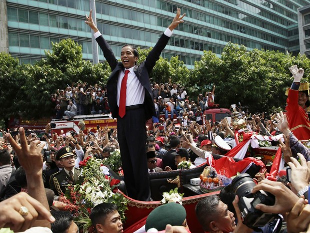 O novo presidente da Indonésia, Joko Widodo, acena para o povo durante passeio em carro aberto após sua posse em Jacarta (Foto: Achmad Ibraham/AP)