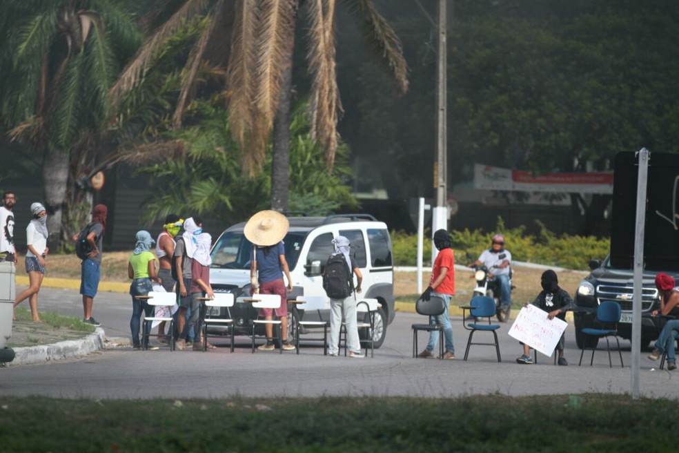 Mascarados, manifestantes mostram cartazes e fecham vias da BR-101 com cadeiras (Foto: Marlon Costa/Pernambuco Press)