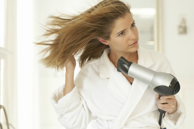 Cabeleireiro seca o cabelo com uma mulher de secador de cabelo no