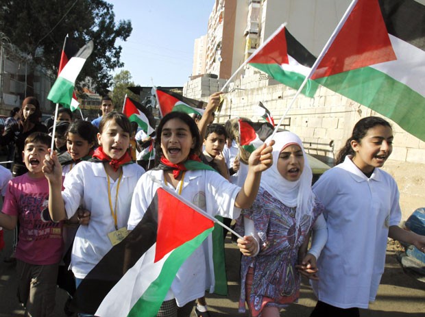 Crianças erguem bandeiras palestinas no campo de refugiados de Shatila na terça-feira (15), marcando o 64º aniversário do Nakba - data que lembra a criação do estado de Israel e suas consequências (Foto: Sharif Karim/Reuters)