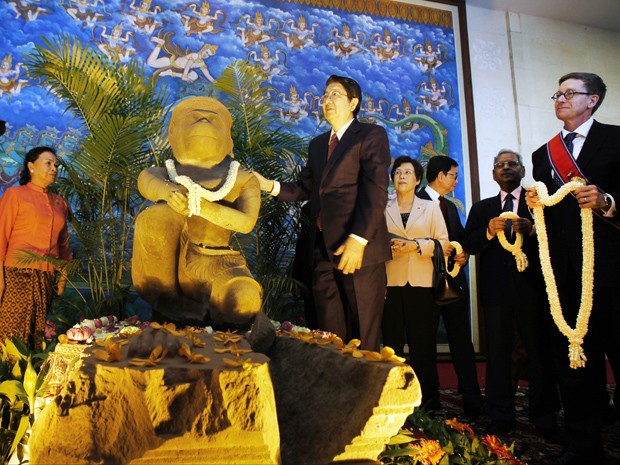 Autoridades cambojanas e o diretor do Cleveland Museum of Art recebem com flores uma estátua do século 10 do deus-macaco hindu Hanuman (Foto: AP Photo/Heng Sinith)