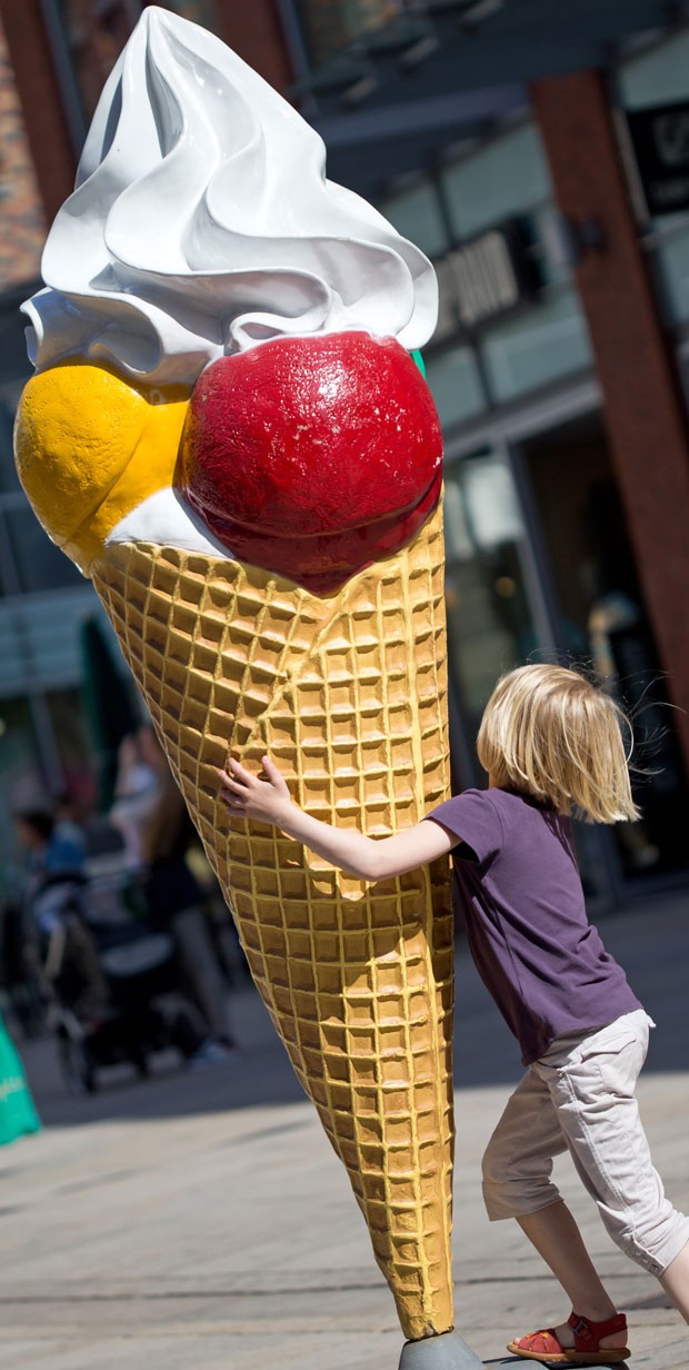 Um menino foi fotografado nesta quinta-feira (6) dando um abraço ao encontrar uma escultura de um sorvete gigante em Osnabrück, na Alemanha (Foto: Friso Gentsch/DPA/AFP)