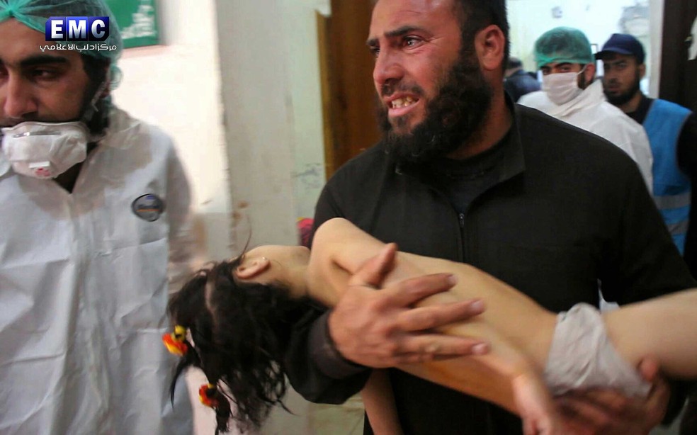 Homem socorre criança após suposto ataque químico em Idlib, no norte da Síria, nesta terça-feira (4)  (Foto: Edlib Media Center, via AP)