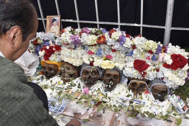  Homem acente velas em frente a crânios humanos em cemitério de La Peza neste domingo (8), quando é celebrado o Dia das Ñatitas  (Foto: AFP Photo/Aizar Raldes)