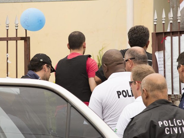 Guilherme Longo sai de viatura e entra na casa onde morava com Natália Ponte e Joaquim (Foto: Érico Andrade/G1)