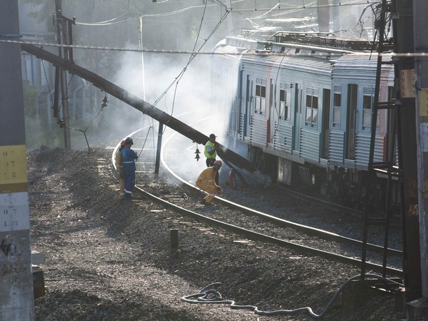Fumaça é vista perto de funcionários da SuperVia e da estrutura de ferro derrubada após o descarrilamento no Rio (Foto: Erbs Jr./Frame/Estadão Conteúdo)