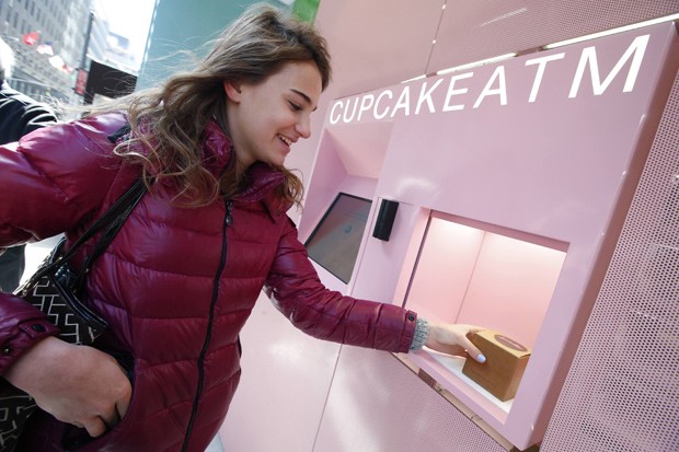 Cliente retira um cupcake de chocolate da máquina de vendas automática, em Nova York (Foto: Reuters/Mike Segar)