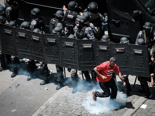 Um manifestante corre para chutar uma bomba de gs jogada pela polcia durante um protesto contra o pacote de austeridade apresentado pelo Governo do Rio de Janeiro em frente  Assembleia Legislativa do Rio (Alerj) (Foto: Yasuyoshi Chiba/AFP)