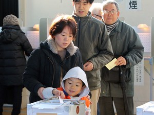 Menino ajuda a mãe a depositar voto em Tóquio, neste domingo (14) (Foto: AFP Photo/Yoshikazu Tsuno) Menino ajuda a mãe a depositar voto em Tóquio, neste domingo (14) (Foto: AFP Photo/Yoshikazu Tsuno)