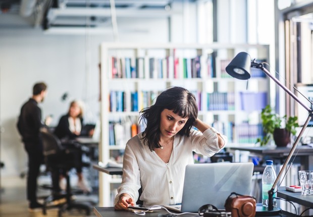 Mulher de negócios olhando laptop enquanto está sentado no escritório (Foto: Mascote via Getty Images)