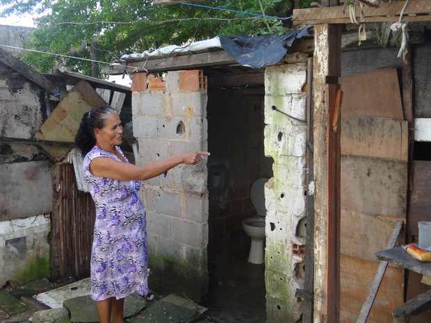 Aposentada Maria José mostra banheiro construído em terreno. (Foto: Carolina Sanches/ G1)