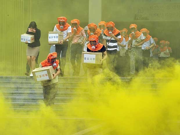 A Coreia do Sul realizou nesta quarta-feira (22) um treinamento de defesa civil em Seul. A simulação usou gás e forçou pessoas a utilizarem máscaras durante o esvaziamento de um edifício e em meio a uma cortina de fumaça. (Foto: Jung Yeon-JE / AFP Photo)