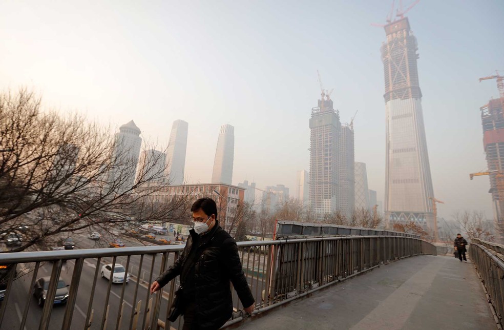 Para se proteger da poluição, homem usa máscara enquanto caminha sobre ponte em Beijing, na China, nesta segunda-feira (19)  (Foto: Andy Wong/ AP)