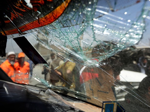 Homens olham através da janela quebrada de um carro-bomba no local de ataque suicida no Cabul, Afeganistão (Foto: AP Photo/Rahmat Gul)