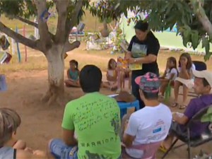 Jaciara lê histórias para as crianças embaixo de uma árvore (Foto: Reprodução/TV Paraíba)