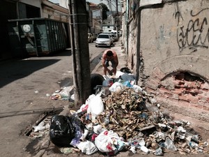 Morador da Rua Presidente Barroso, na Cidade Nova, coloca mais um saco de lixo na pilha da calçada, esquina com a Avenida Salvador de Sá. (Foto: Guilherme Brito / G1)