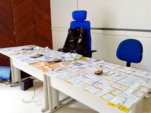 Folhas de cheque com valores diferentes e R$ 1.254 em espécie (Foto: Polícia Civil)