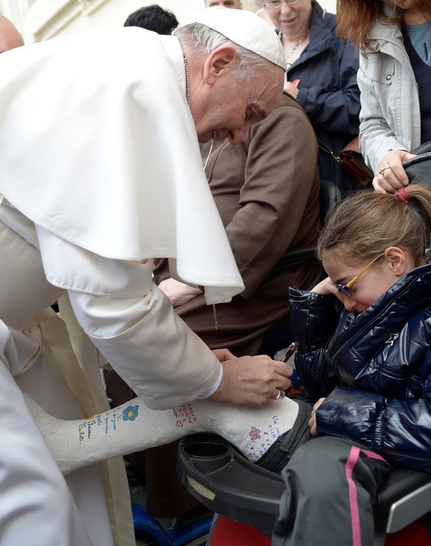 Papa Francisco autografa gesso de jovem na Praça São Pedro (Foto: Osservatore Romano/AFP)