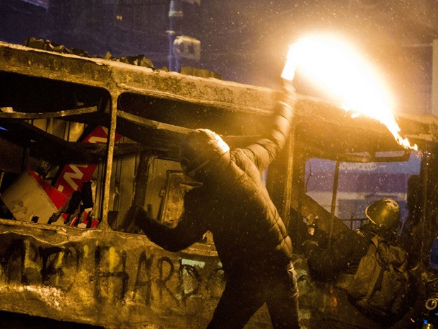 Manifestante joga coquetel molotov contra policiais em Kiev, na Ucrânia, nesta quarta-feira (22). (Foto: Evgeny Feldman/AP)